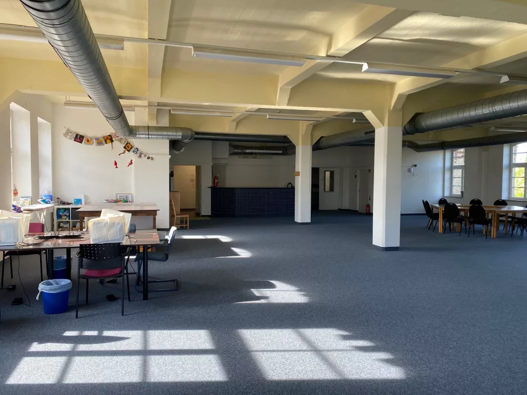 Ein großer Saal mit Tischgruppen, Blick zur Tür