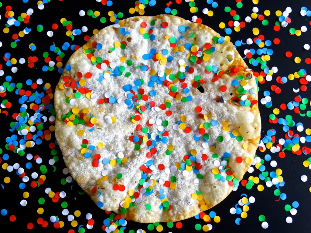 Konfetti über einem runden Gebäckstück, mit schwarzem Hintergrund