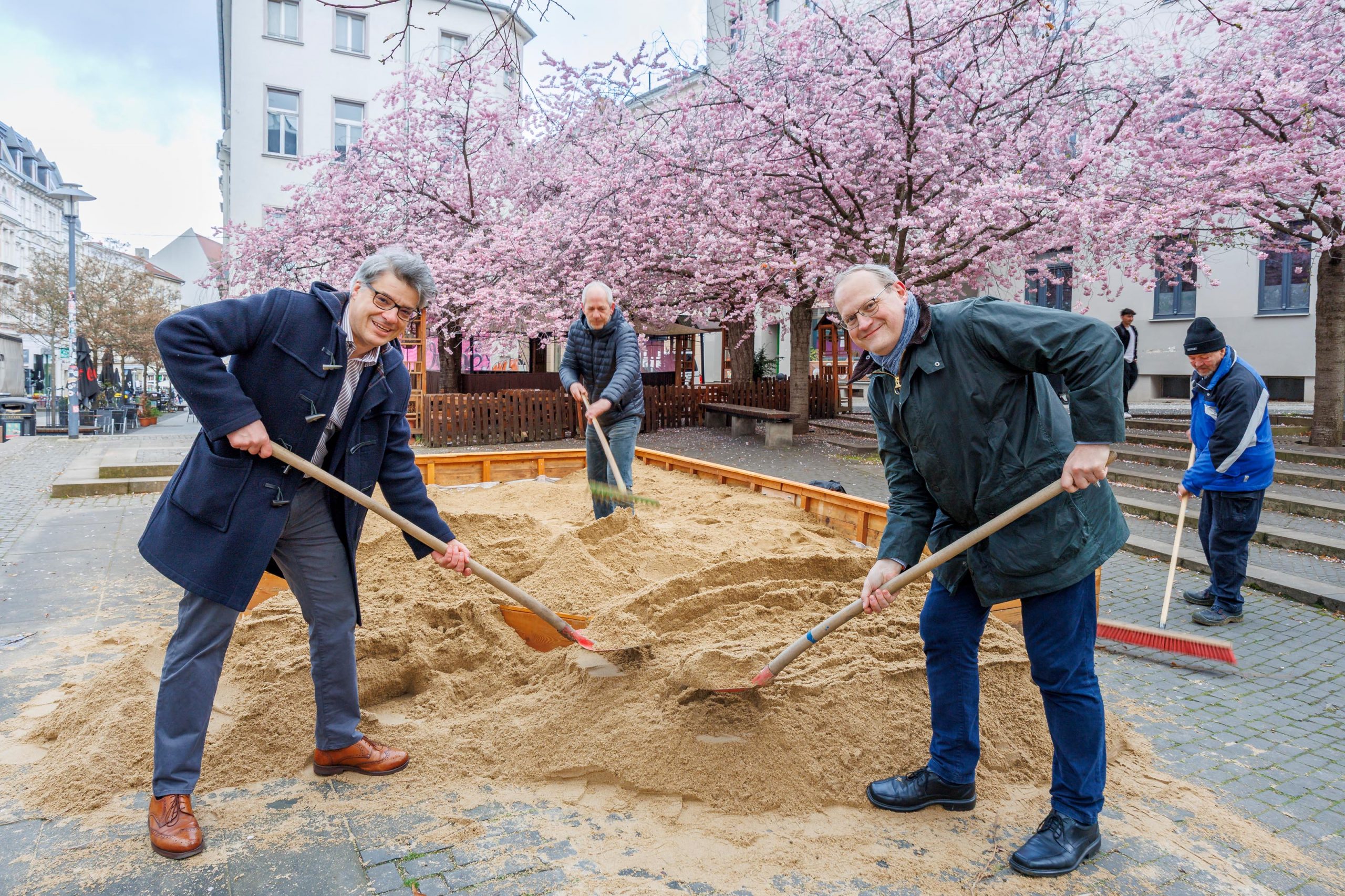vier Männer schaufeln Sand